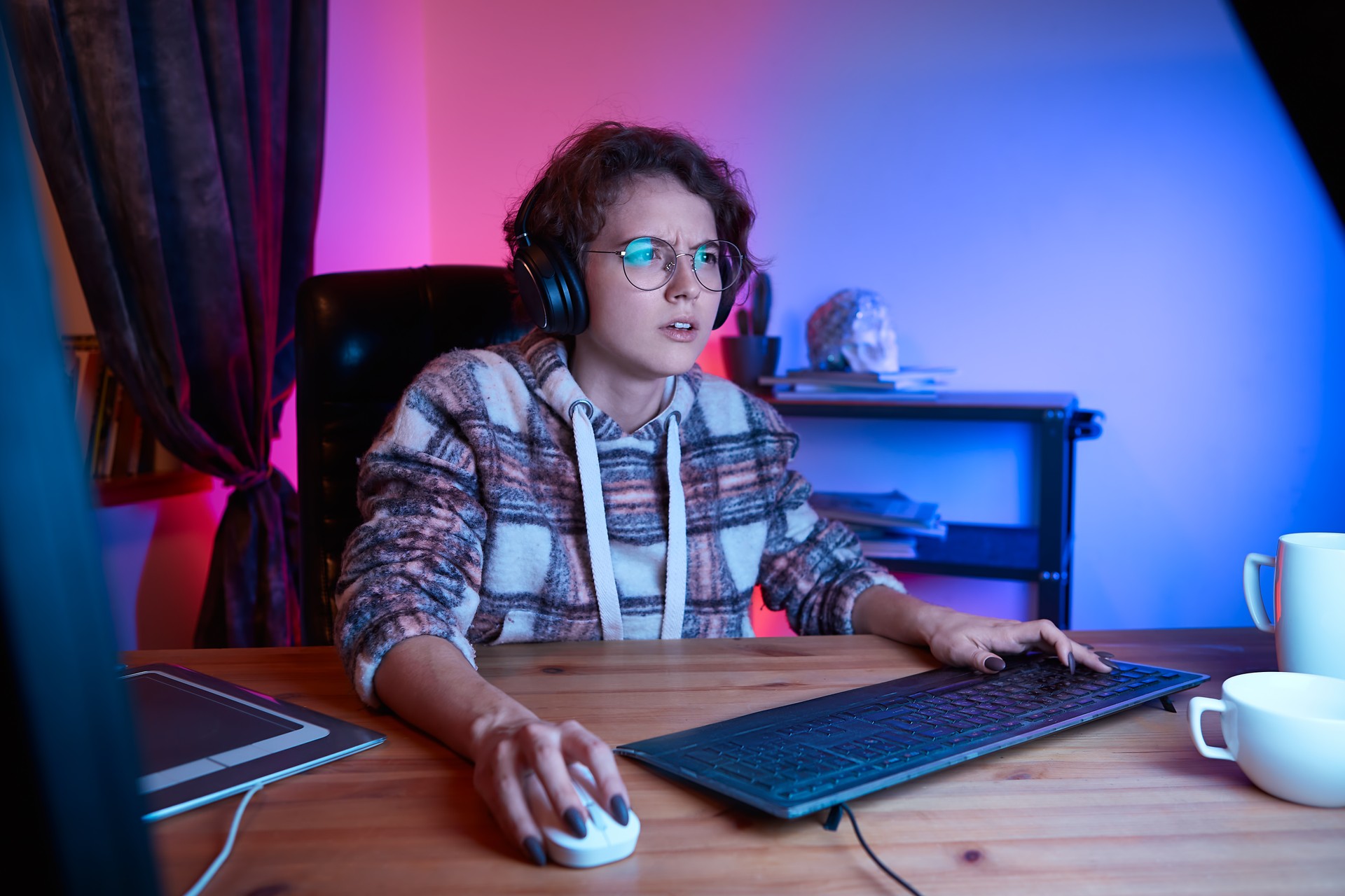 Confused girl looking at the screen of a computer sitting in a cosy chair at home. Work from home