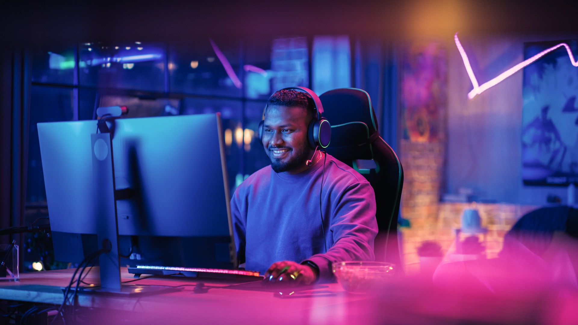 Gaming From Home: Portrait of a Gamer Wearing Headphones and Playing Competitive Video Game on Personal Computer. Professional Stylish Male Player Enjoying Online Multiplayer PvP Tournament.